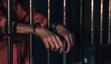 negative-space-two-hands-in-handcuffs-lean-on-bars-of-a-prison-cell-scaled-e1641283066427.jpg